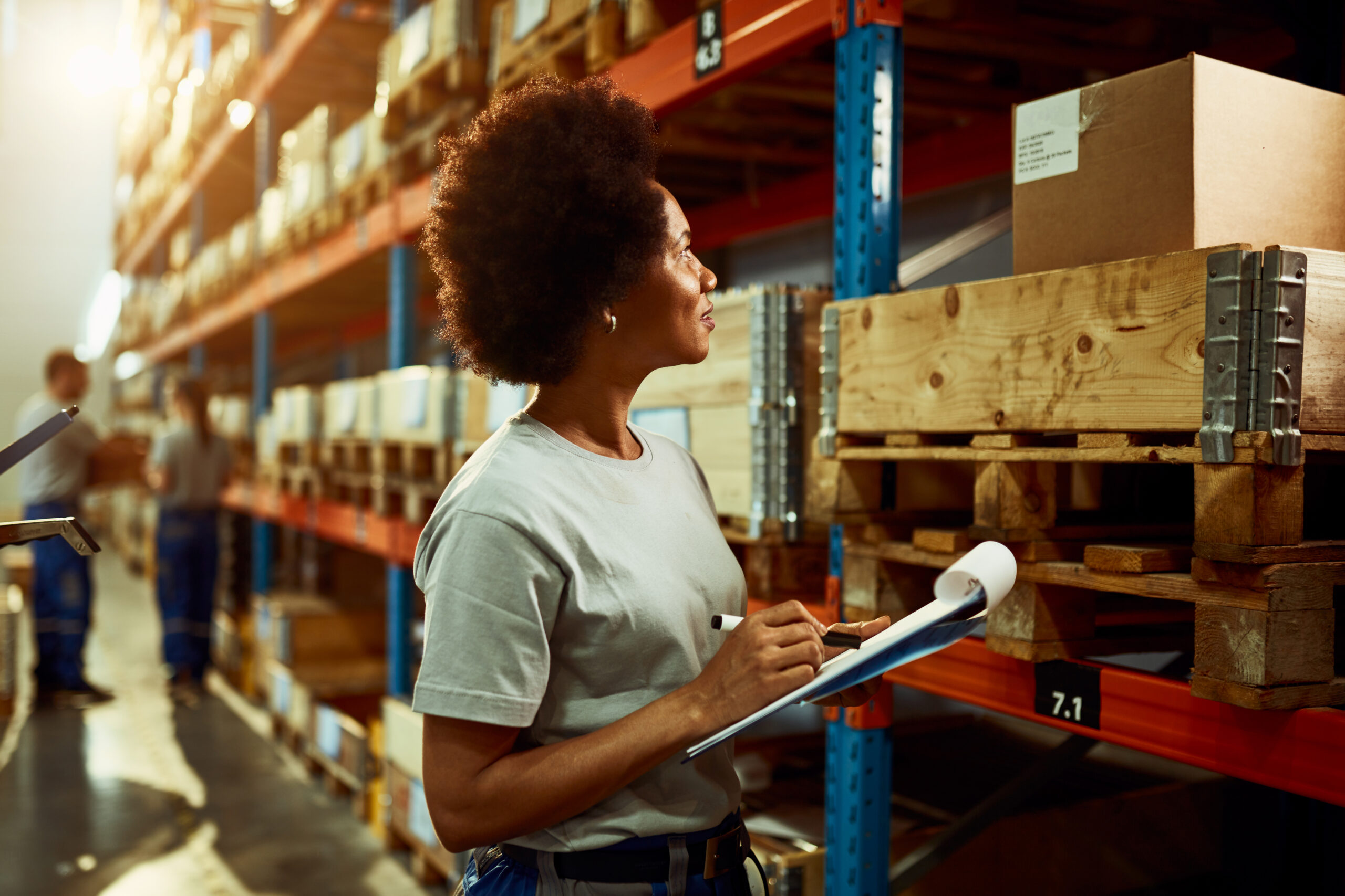 african american worker writing inventory list while checking stock storage room scaled